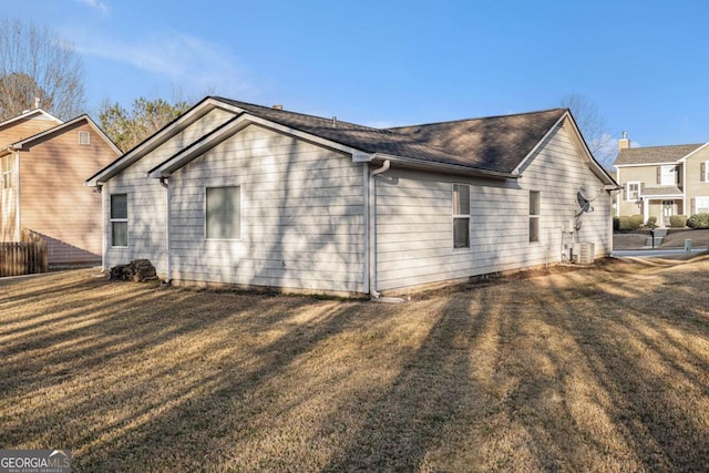 view of side of home with a lawn and central AC