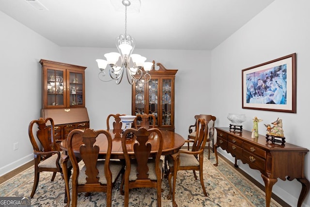 dining area featuring wood finished floors, visible vents, baseboards, and a chandelier