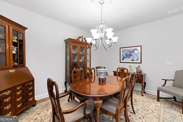 dining space featuring light wood-style flooring, baseboards, and a chandelier