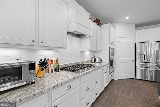 kitchen with custom exhaust hood, backsplash, white cabinetry, and stainless steel appliances