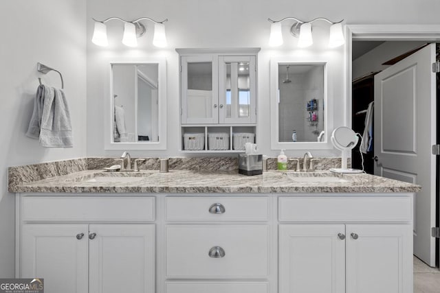 bathroom with a sink, double vanity, and a tile shower