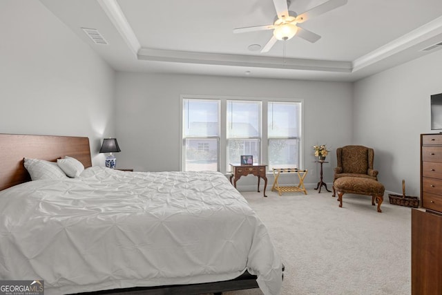 carpeted bedroom with visible vents, ceiling fan, baseboards, and a tray ceiling