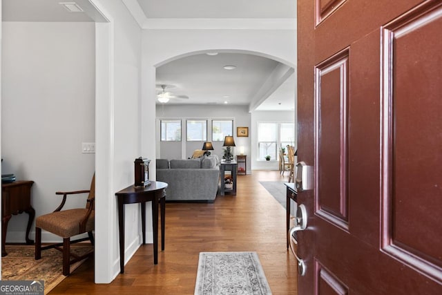 entryway featuring arched walkways, dark wood-type flooring, and a ceiling fan