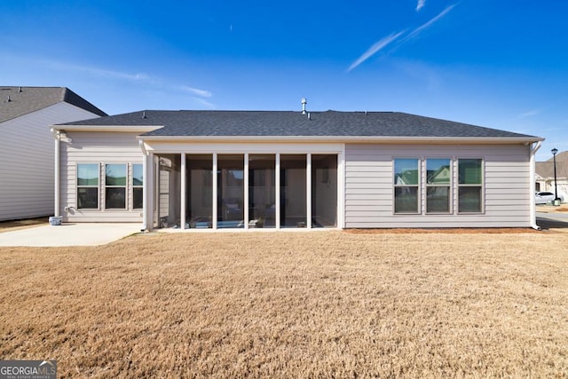 back of property with a lawn, a shingled roof, a patio, and a sunroom