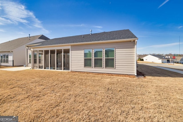 back of house with a yard, a shingled roof, and a sunroom