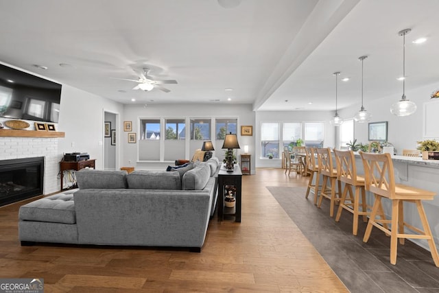 living area featuring recessed lighting, a fireplace, dark wood-style flooring, and ceiling fan