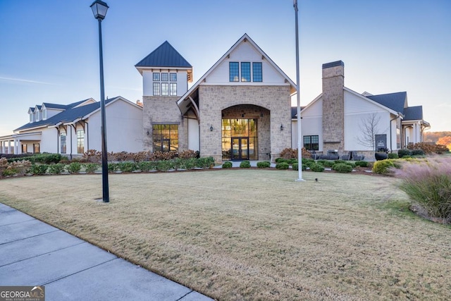 view of front of house featuring a standing seam roof, a front lawn, brick siding, and metal roof