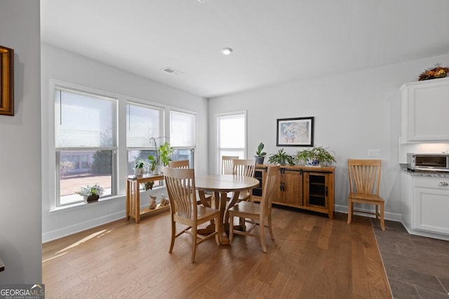 dining area with a toaster, visible vents, dark wood-type flooring, and baseboards