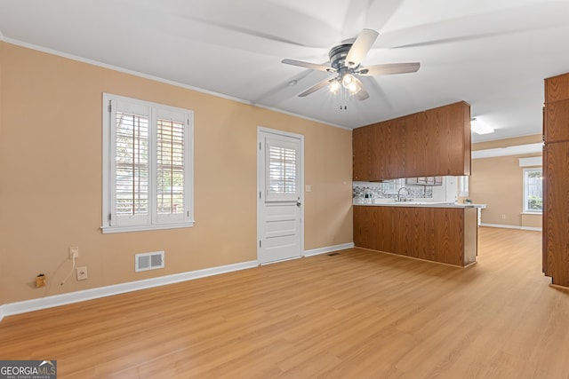 kitchen featuring tasteful backsplash, brown cabinets, crown molding, and light wood finished floors