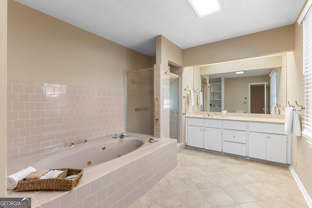 bathroom featuring a textured ceiling, tile patterned flooring, vanity, a jetted tub, and a stall shower