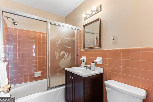 full bath with toilet, shower / bath combination with glass door, vanity, and tile walls