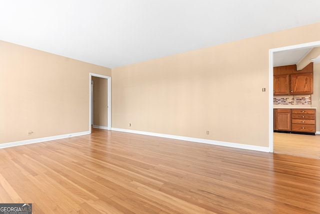 unfurnished living room featuring light wood finished floors and baseboards