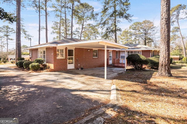 view of front of home with a carport, brick siding, and driveway