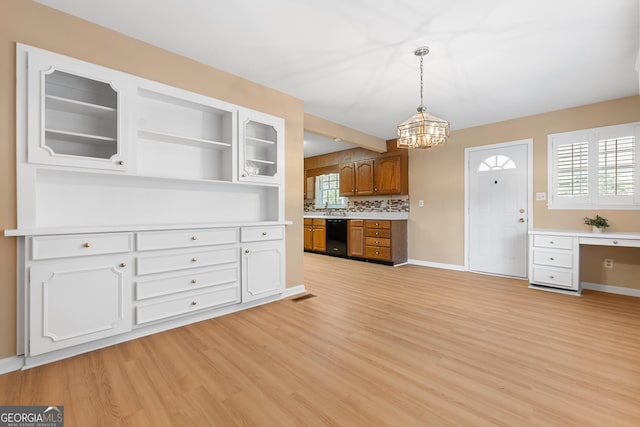 kitchen with baseboards, brown cabinetry, hanging light fixtures, light countertops, and light wood-type flooring