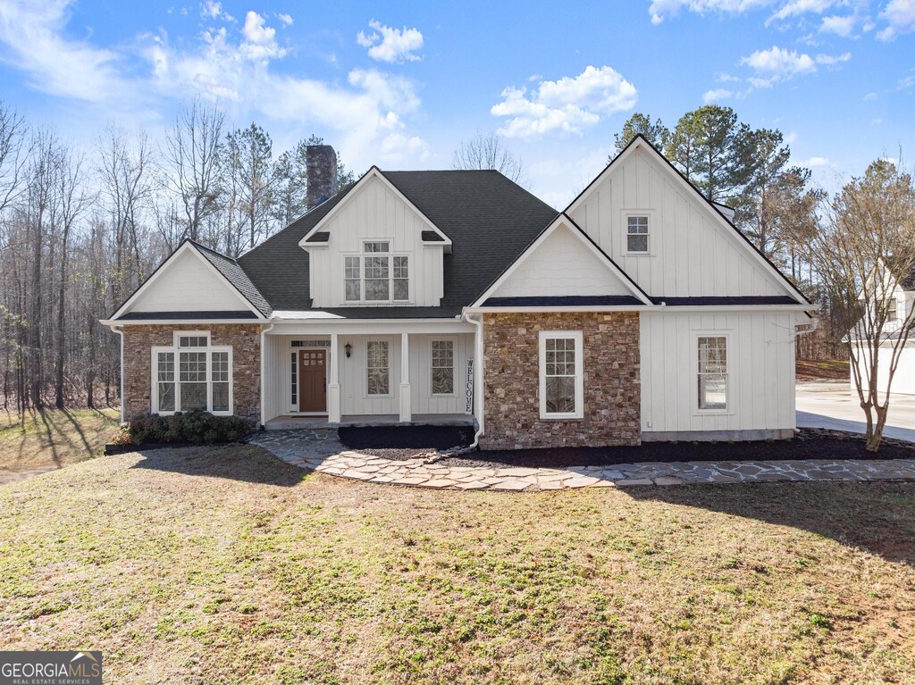 view of front of house featuring a front yard, board and batten siding, and a chimney