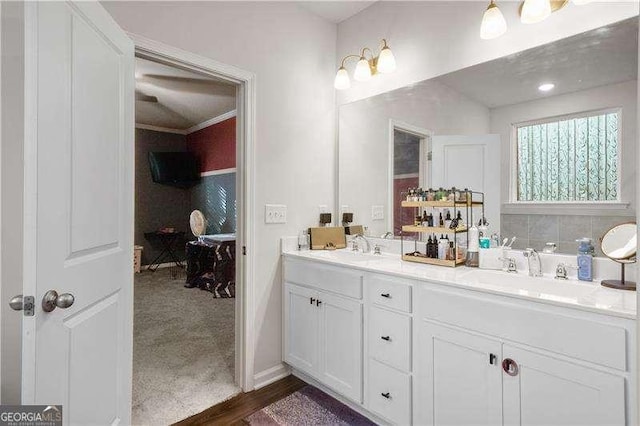 full bath featuring wood finished floors, a sink, baseboards, and double vanity