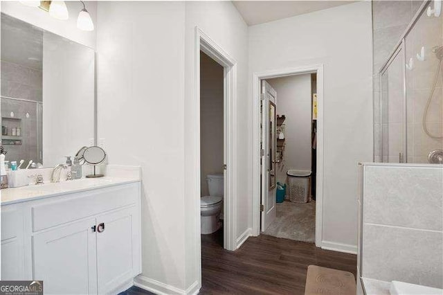 full bath featuring toilet, a shower stall, wood finished floors, and vanity