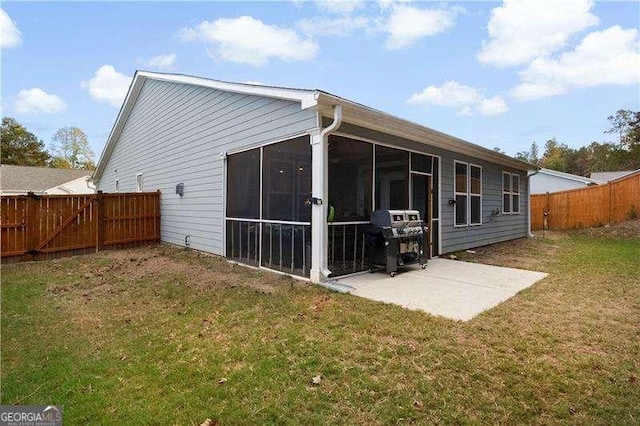 rear view of property with a yard, a patio area, a fenced backyard, and a sunroom