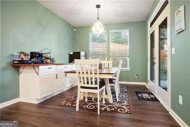 dining area with dark wood-style floors, a chandelier, and baseboards