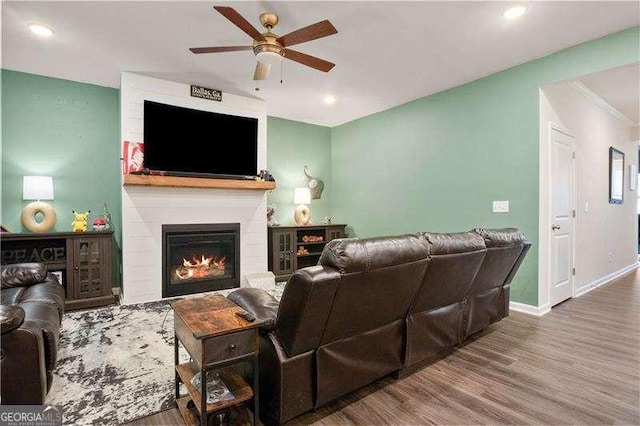 living room with ceiling fan, recessed lighting, wood finished floors, baseboards, and a glass covered fireplace