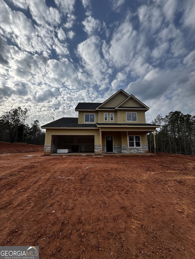 view of front of house featuring a garage, covered porch, and stone siding