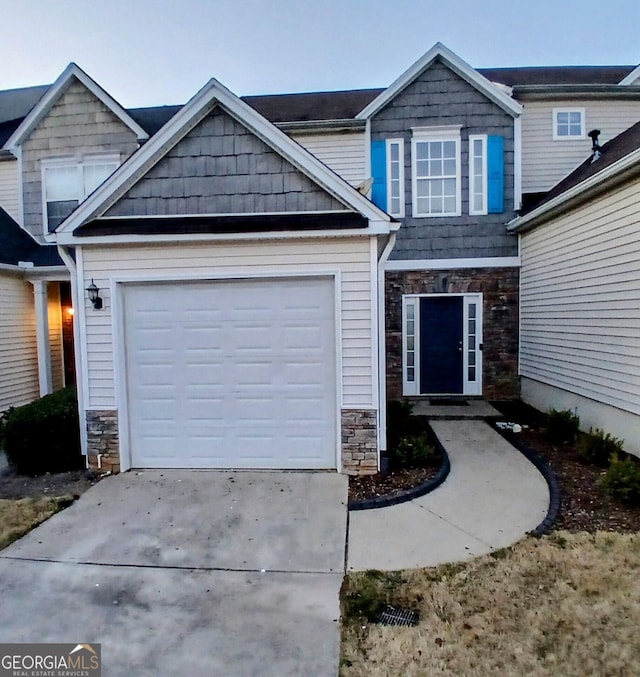 craftsman-style home with a garage, stone siding, and concrete driveway