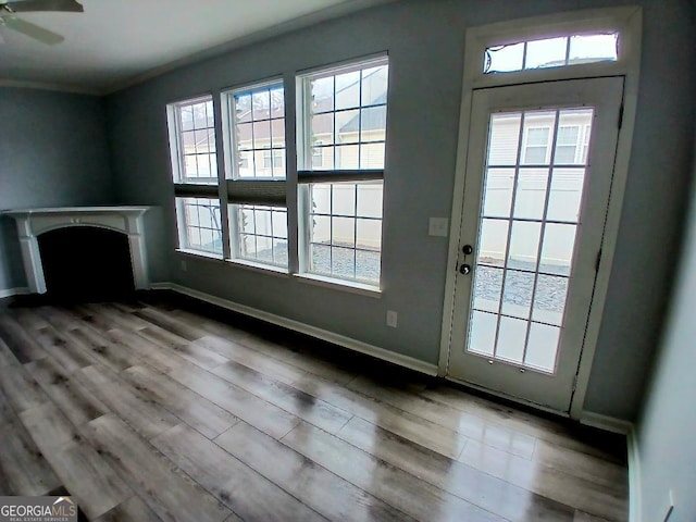 unfurnished living room featuring ceiling fan, wood finished floors, and baseboards