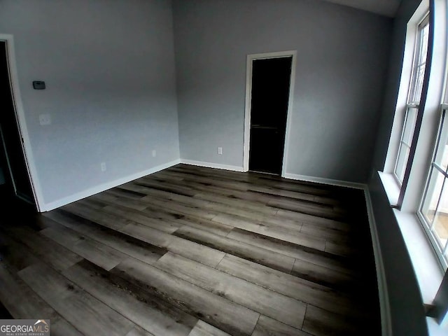 unfurnished room featuring dark wood-style flooring and baseboards