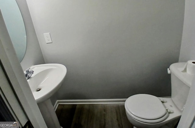 half bath with wood finished floors, toilet, and baseboards