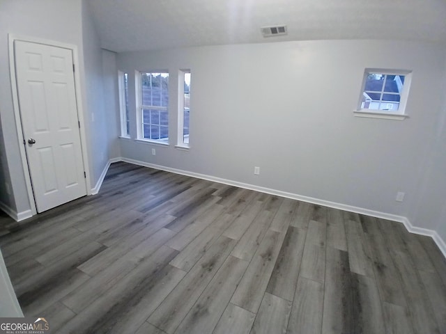 unfurnished bedroom with dark wood-style flooring, visible vents, baseboards, and multiple windows