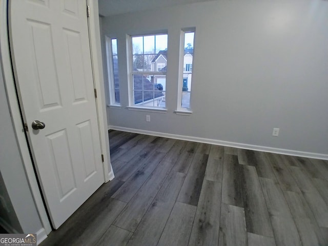 empty room with dark wood-style floors and baseboards