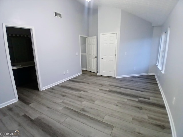 unfurnished bedroom featuring ensuite bathroom, wood finished floors, visible vents, and baseboards