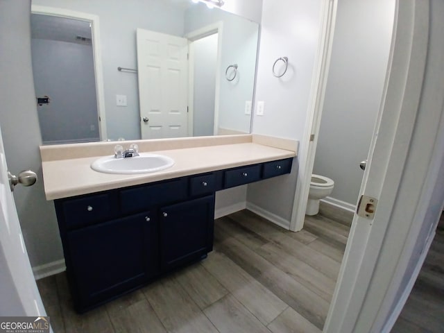 bathroom featuring vanity, wood finished floors, toilet, and baseboards