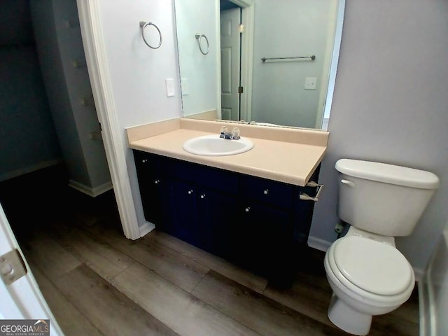 bathroom with toilet, baseboards, wood finished floors, and vanity