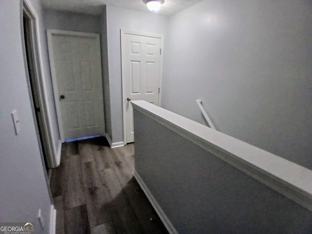 corridor featuring wood finished floors, an upstairs landing, and baseboards