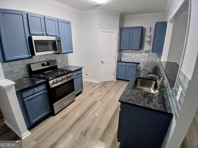 kitchen featuring stainless steel appliances, tasteful backsplash, light wood-style floors, a sink, and dark stone countertops