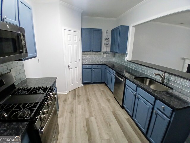 kitchen featuring light wood finished floors, appliances with stainless steel finishes, ornamental molding, blue cabinetry, and a sink