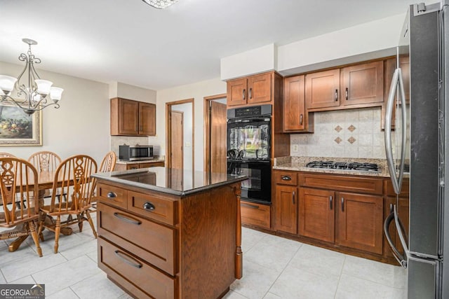 487 Glendale Ct, Stone Mountain, GA 30087 - kitchen featuring dark stone counters, a kitchen island, brown cabinets, stainless steel appliances, and backsplash