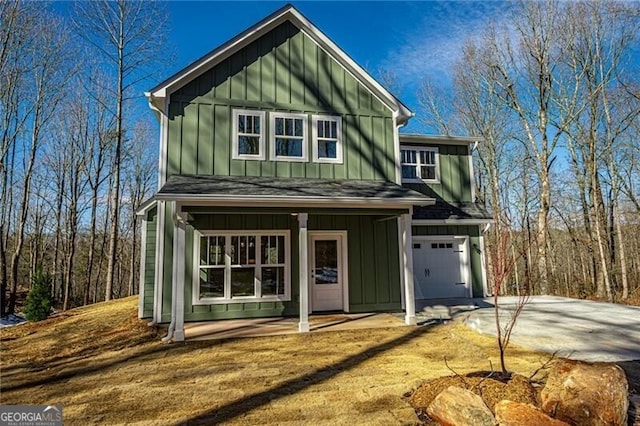 view of front of house with covered porch, a garage, driveway, roof with shingles, and board and batten siding