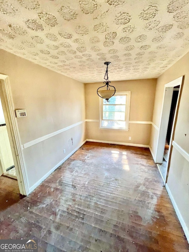 unfurnished dining area with wood finished floors and baseboards