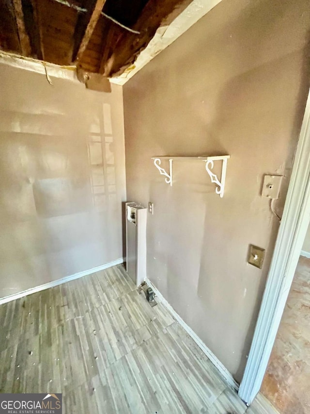 laundry area featuring radiator heating unit, wood finished floors, and baseboards