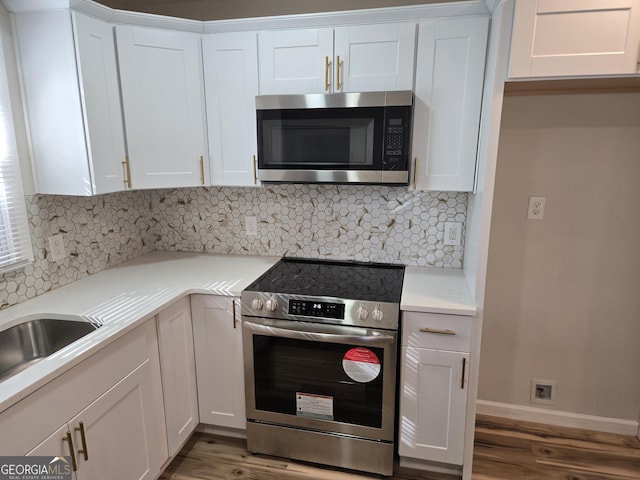 938 Rebel Forest Dr SE, Atlanta, GA 30315 - kitchen with baseboards, decorative backsplash, wood finished floors, stainless steel appliances, and white cabinetry