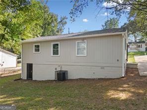 rear view of property with central AC and a lawn