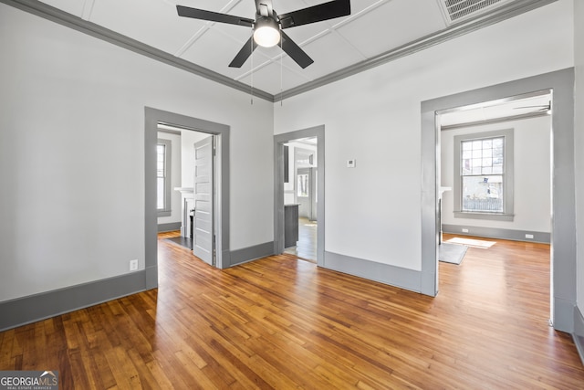 empty room featuring a fireplace, visible vents, hardwood / wood-style floors, ceiling fan, and baseboards
