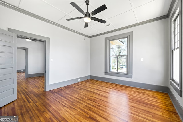 spare room featuring ornamental molding, wood-type flooring, visible vents, and baseboards