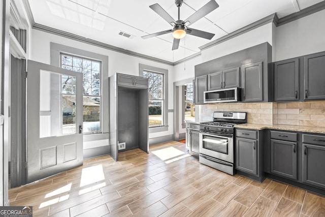 kitchen featuring tasteful backsplash, visible vents, appliances with stainless steel finishes, ornamental molding, and wood tiled floor