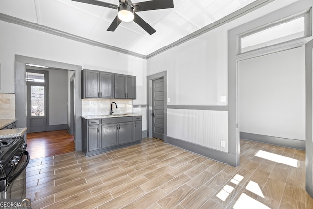 kitchen with stove, a sink, backsplash, light stone countertops, and wood tiled floor