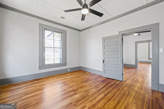 spare room with baseboards, wood-type flooring, visible vents, and a ceiling fan