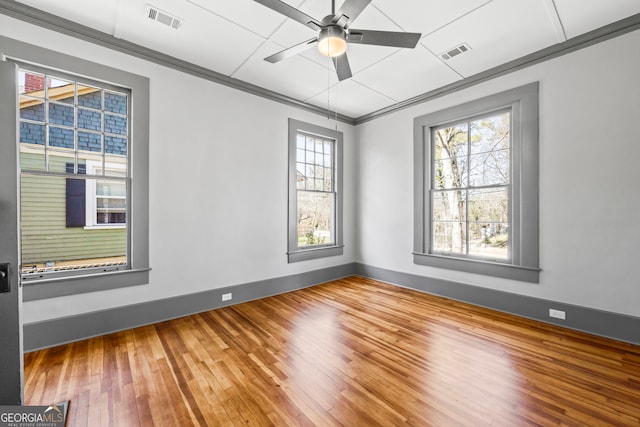 spare room with a ceiling fan, visible vents, crown molding, and hardwood / wood-style flooring