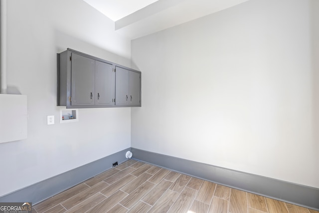 laundry area with cabinet space, hookup for a washing machine, baseboards, and wood finish floors
